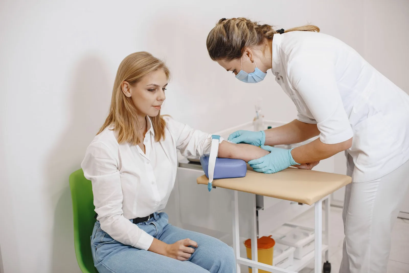 Hoitaja ottaa verinäytettä naisen käsivarresta laboratoriossa