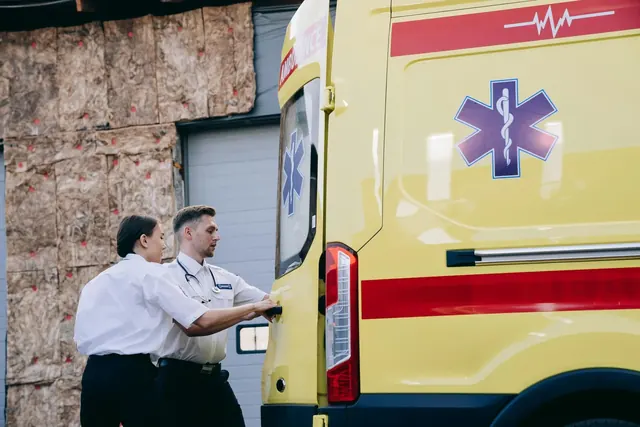 Ensihoitajat sulkevat ambulanssin takaovia hälytystehtävää valmistellessaan