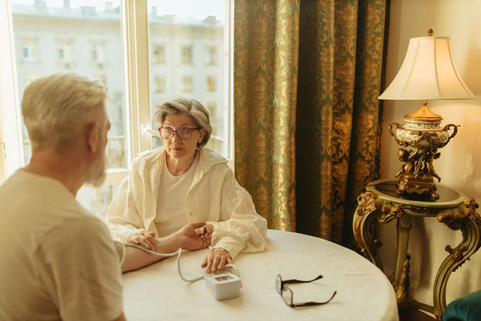 Iäkäs pariskunta mittaa verenpainetta kotona pöydän ääressä